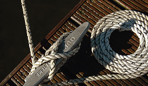 A cleat and a coiled rope on a jetty